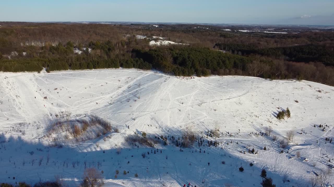 Ampia ripresa con drone che sorvola un parco ricreativo collinare all'aperto coperto di neve.