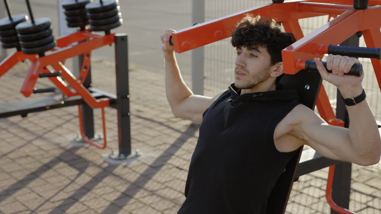 Man working out outdoors on a shoulder press machine.