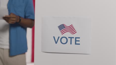 vote sign on ballot box in american election with man deciding how to cast his vote in background