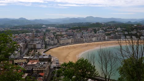Aerial-panoramic-shot-of-beautiful-skyline-in-San-Sebastián-during-sunny-day-in-Spain---Beautiful-mountain-range-and-cityscape-in-background