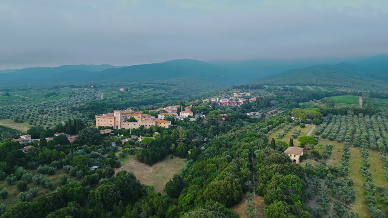 antiguo asentamiento toscano en la ladera por encima de los campos de la granja de huertos en el campo italiano