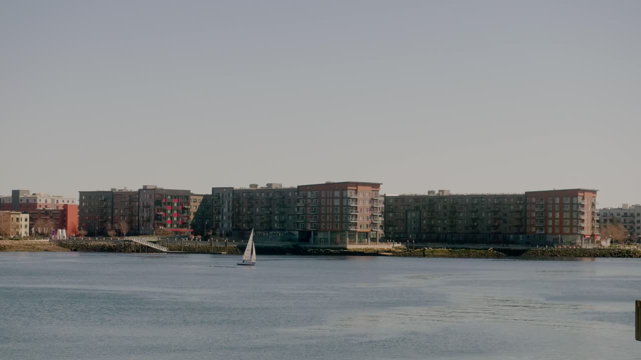 Luxury Apartments At Waterfront Of East Boston With Sailboat Sailing On Boston Harbor In Massachusetts, USA. wide shot