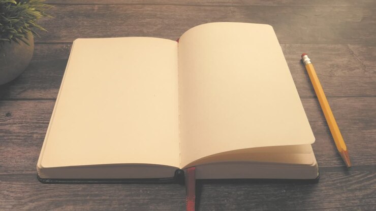 Open Notebook on Wooden Table with Pencil and Plant
