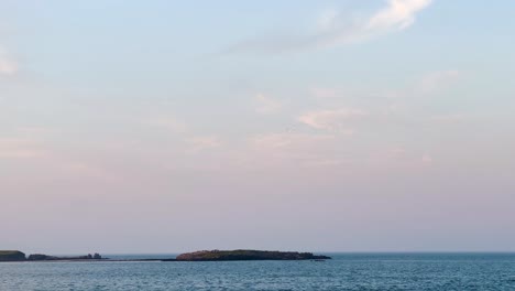 Golden-Hour-Serenity:-Seagull-Soaring-Over-Howth-Pier,-Ireland,-Embracing-Nature's-Beauty-and-Maritime-Tranquility-at-Sunset-With-Ireland's-Eye-In-The-Background