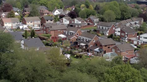 quiet british homes and gardens residential suburban property aerial view dolly right above trees