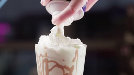 spraying whipped cream over a chocolate milkshake