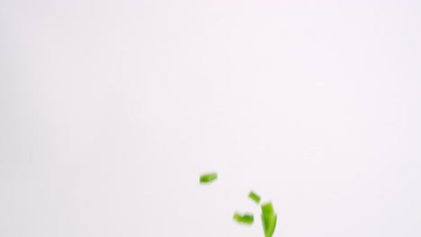 bright green chopped bell pepper vegetable cubes raining down on white backdrop in slow motion