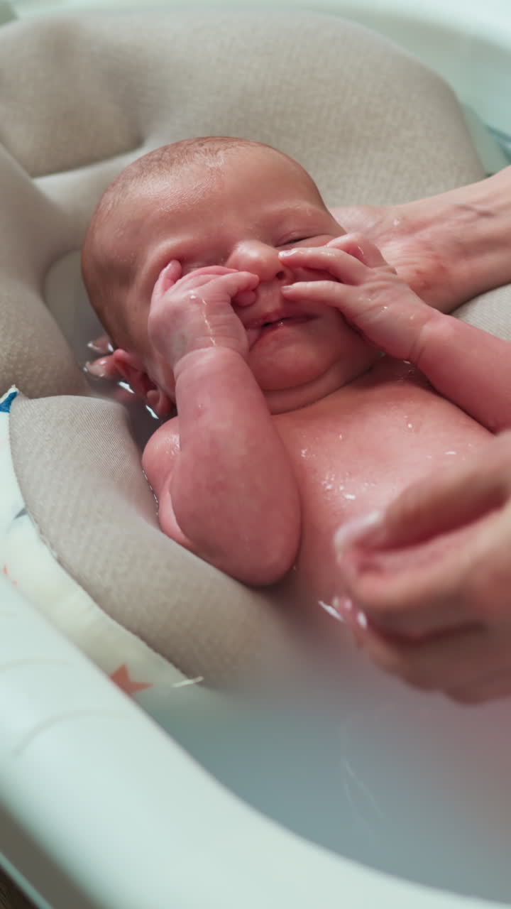 Le mani dei genitori lavano delicatamente il neonato in acqua tiepida, sostenendo la testa e il corpo per garantire comfort e sicurezza