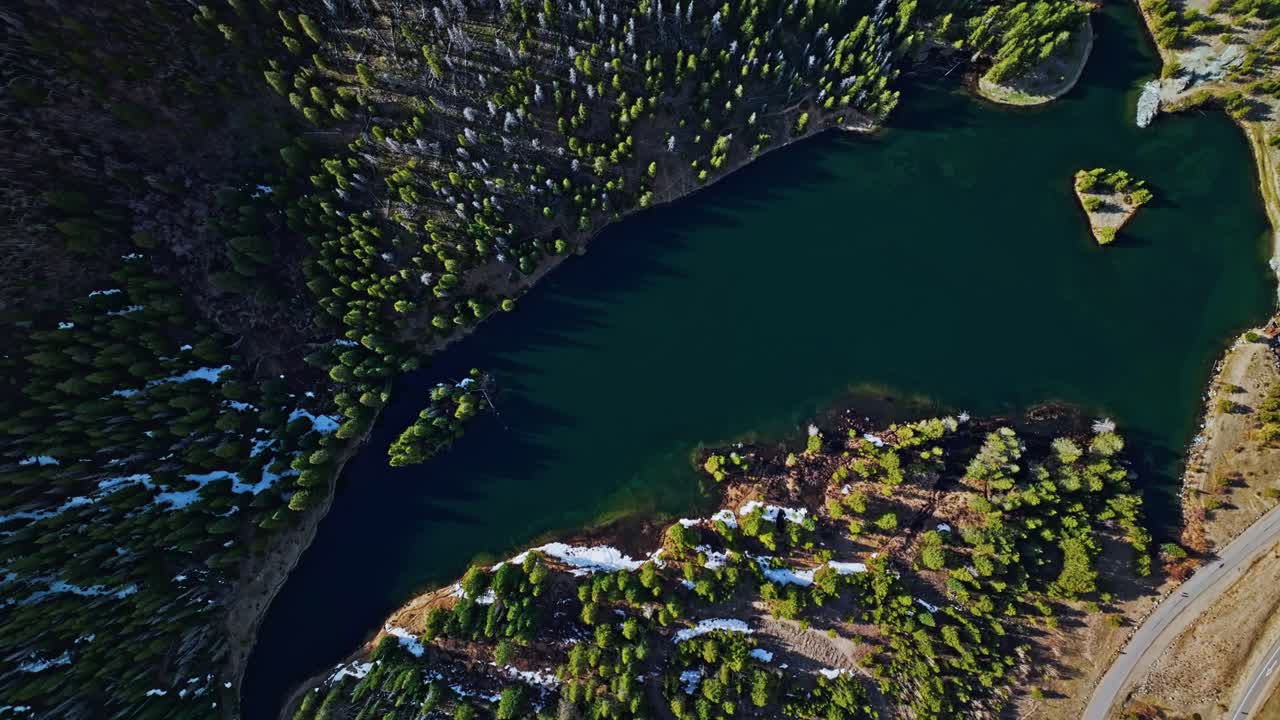 Aerial top down ascend of reflective alpine lake and pine forest deep in Frisco Gulch Colorado USA, natural backdrop background