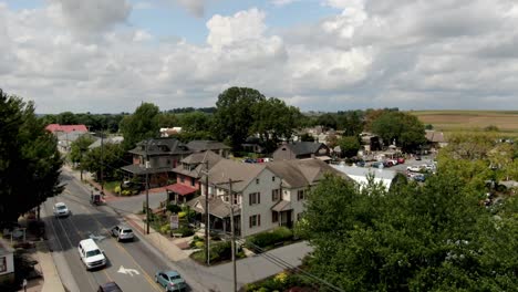 Rising-aerial-of-Amish-horse-and-buggy-on-road-with-traffic-in-Intercourse,-Pennsylvania,-USA