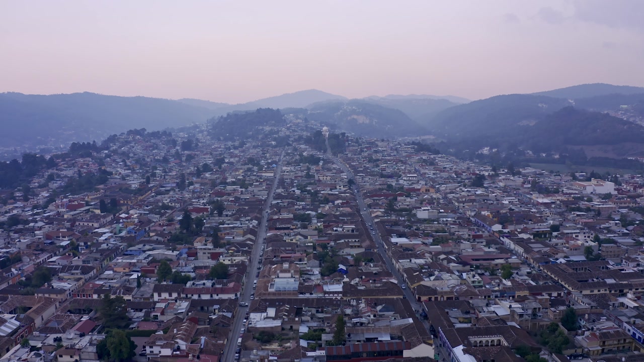 An aerial drone shot captures the charming colonial city of San Cristóbal de las Casas in Chiapas, Mexico, at sunset.