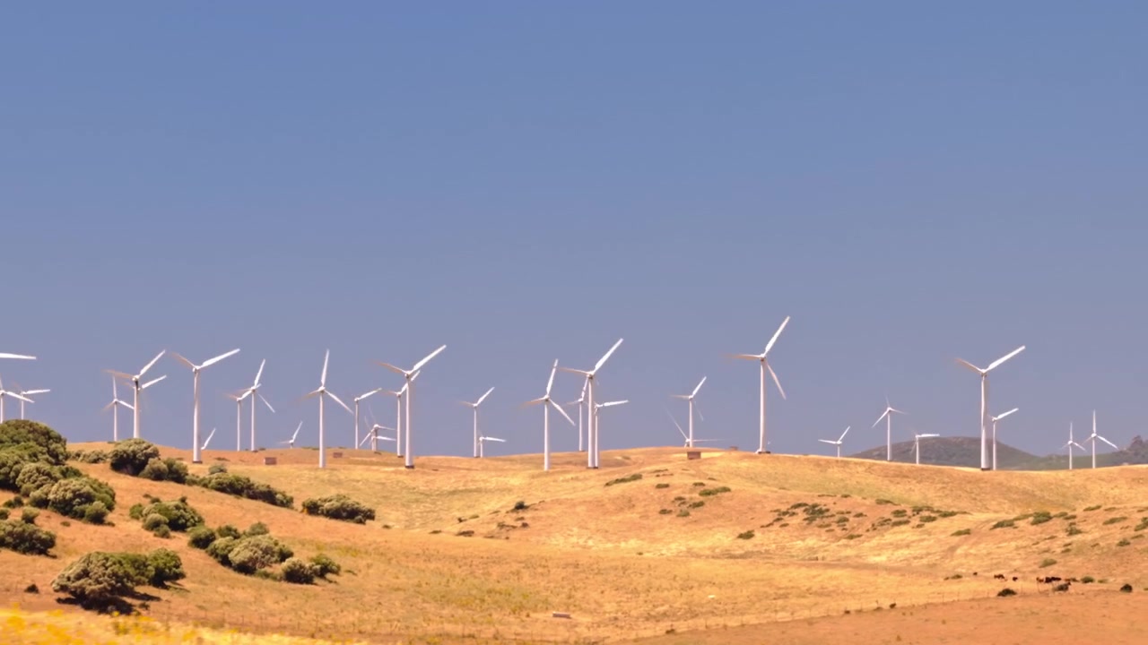 Images cinématographiques par drone d'un grand parc éolien avec des éoliennes générant de l'électricité propre et renouvelable à travers un paysage rural. Infrastructure énergétique durable soutenant la décarbonisation et les objectifs climatiques.