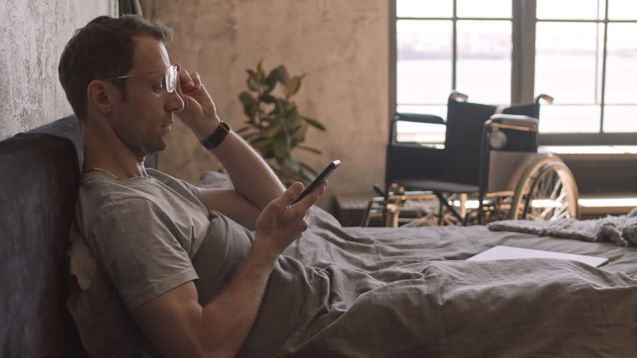 Man Talking on Speaker Phone in Bed