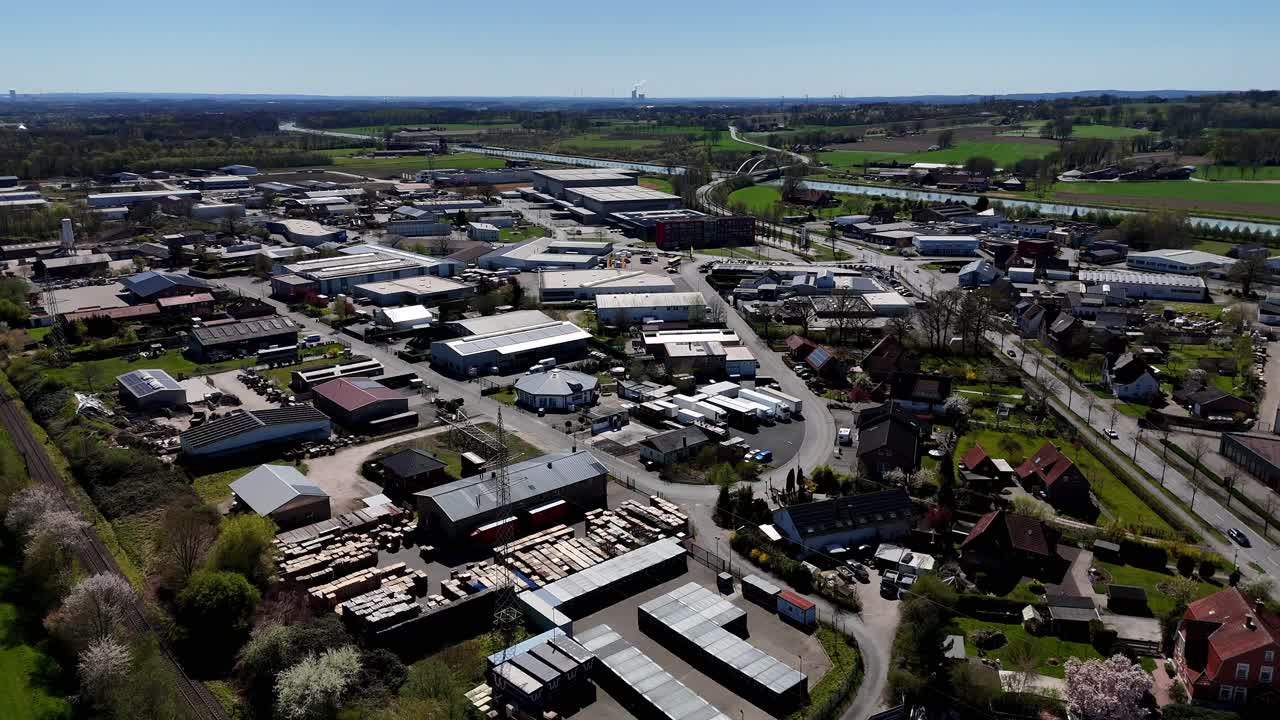 Industrial area in american suburb town during sunny day in spring. Rooftops of factory and companies. River and farm fields in background. Rural area in USA. Aerial forward wide shot.