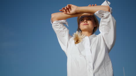 una chica con los ojos cerrados posando en la naturaleza retrato vertical. una mujer rubia feliz posando sola