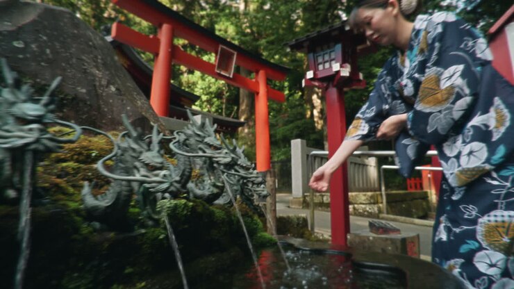 Donna che usa la fontana del drago in un tempio giapponese