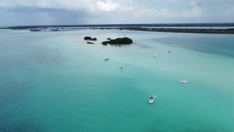 boats navigating the clear blue waters of bacalar lagoon in mexico, aerial view