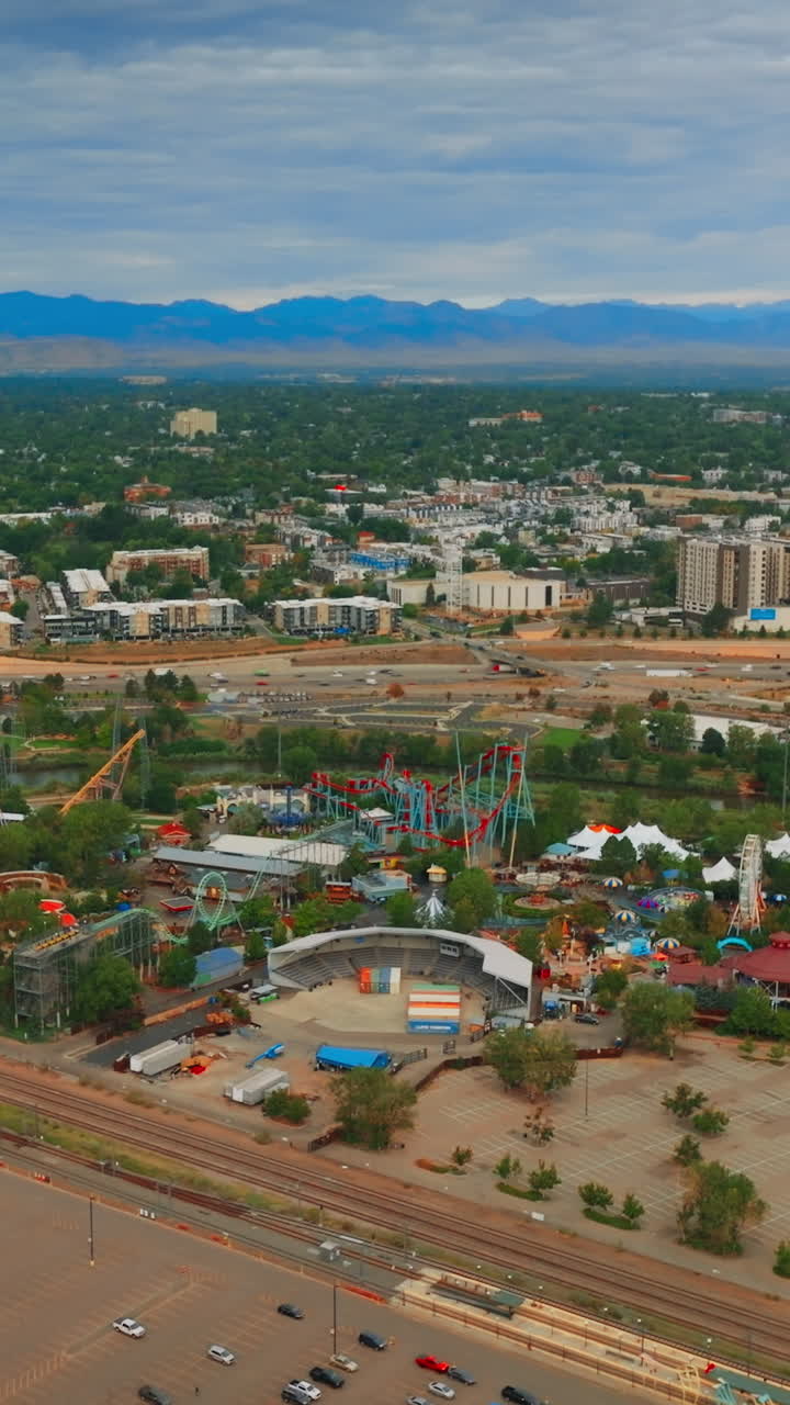 Flying above huge almost empty parking lot with few cars only. View of the big amusement park in Denver, Colorado, USA. Aerial perspective. Vertical video