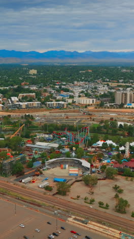 flying above huge almost empty parking lot with few cars only. view of the big amusement park in denver, colorado, usa. aerial perspective. vertical video