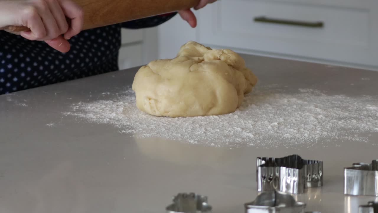 A close up shot of a large ball of cookie dough being rolled out on a kitchen counter in preparation to make Christmas cookies
