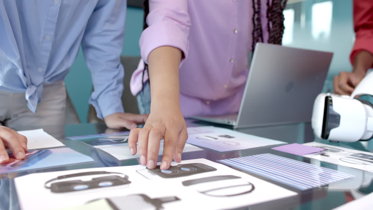 Reviewing VR headset designs, colleagues collaborating and using laptop in office