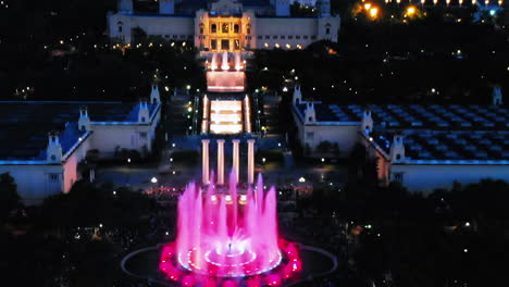 aerial view, fountains of monjuic colorfull at night from above, revealing the city, barcelona, spain