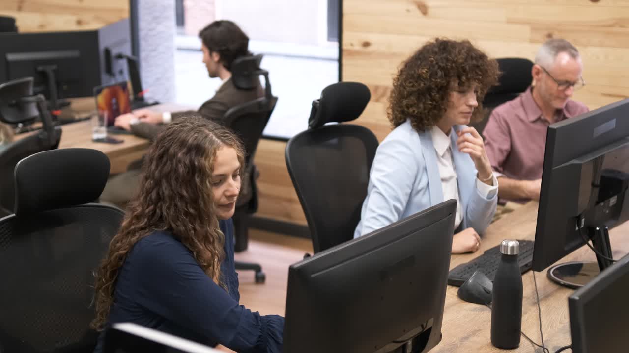Business people using computers at tables in workplace