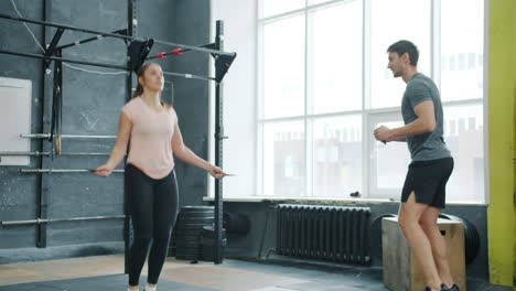 woman jumping rope with personal trainer in gym