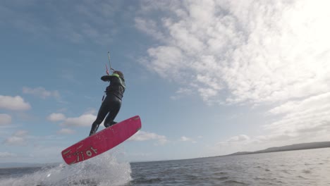 kitesurfer spinning into the air on a sunny day at the beach in sardinia, italy - action shot, slow motion