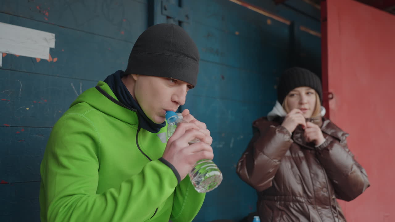 운동 팀이 고요함 속에서 함께 휴식을 취하고, 팀원들은 하던 활동을 멈추고 물을 마시며 휴식을 취해요. 선수들은 예정된 휴식 시간 동안 편안하게 대화를 나누면서 휴식을 취하는 평온한 시간을 가져요.