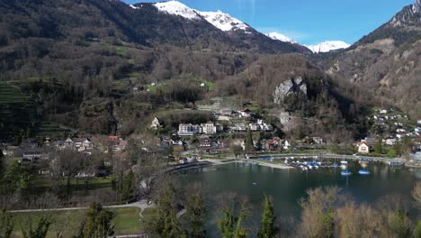 drone clip moving away from lake walen and hillside village of weesen, st gallen, with picturesque snowcapped mountains in the background