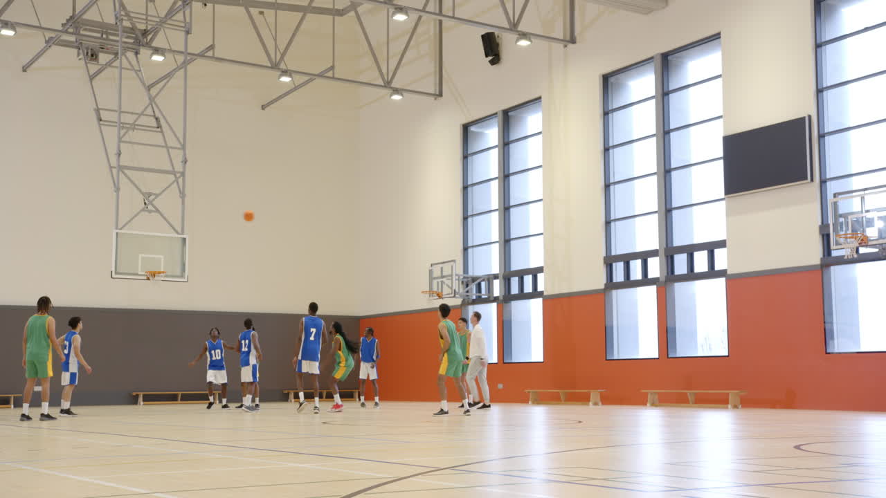 Basketbal spelen in de sporthal, studenten oefenen een wedstrijd met coach op school.
