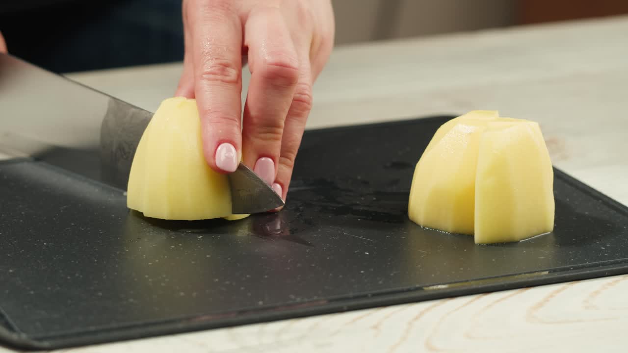 Woman cutting potato on table in kitchen. High quality 4k footage