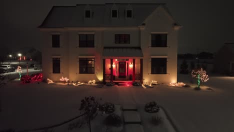 aerial view of snow-covered single family house decorated and lighting with festive lights