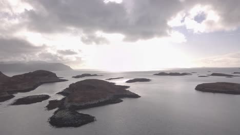 aerial shot flying south, over the island of ulva, towards the isle of mull with archipelago islands on a overcast day on the west coast of scotland