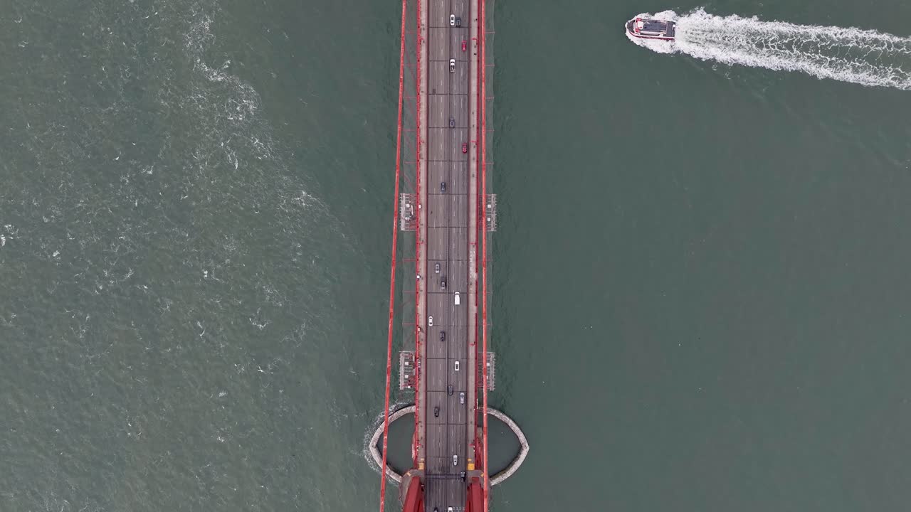 Aerial directly above Golden Gate Bridge as ferry boat crosses the strait
