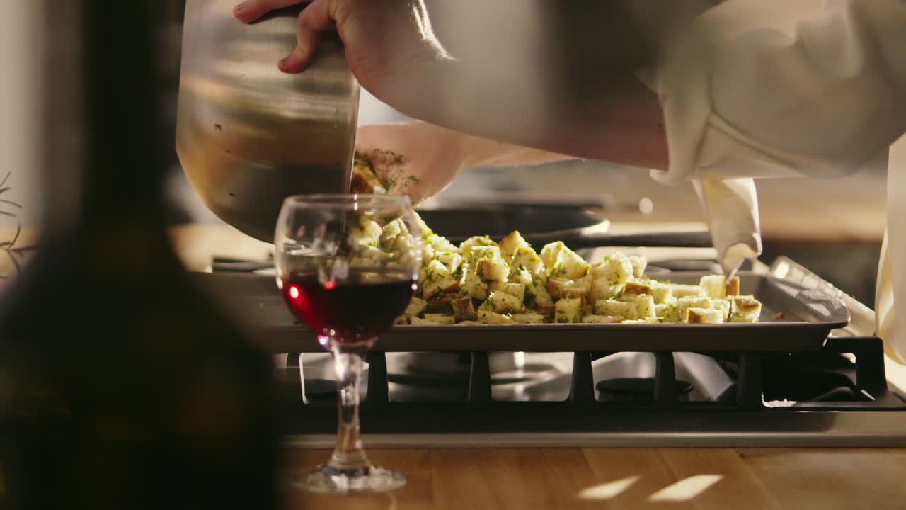 Uno chef versa crostini alle erbe su una teglia da forno