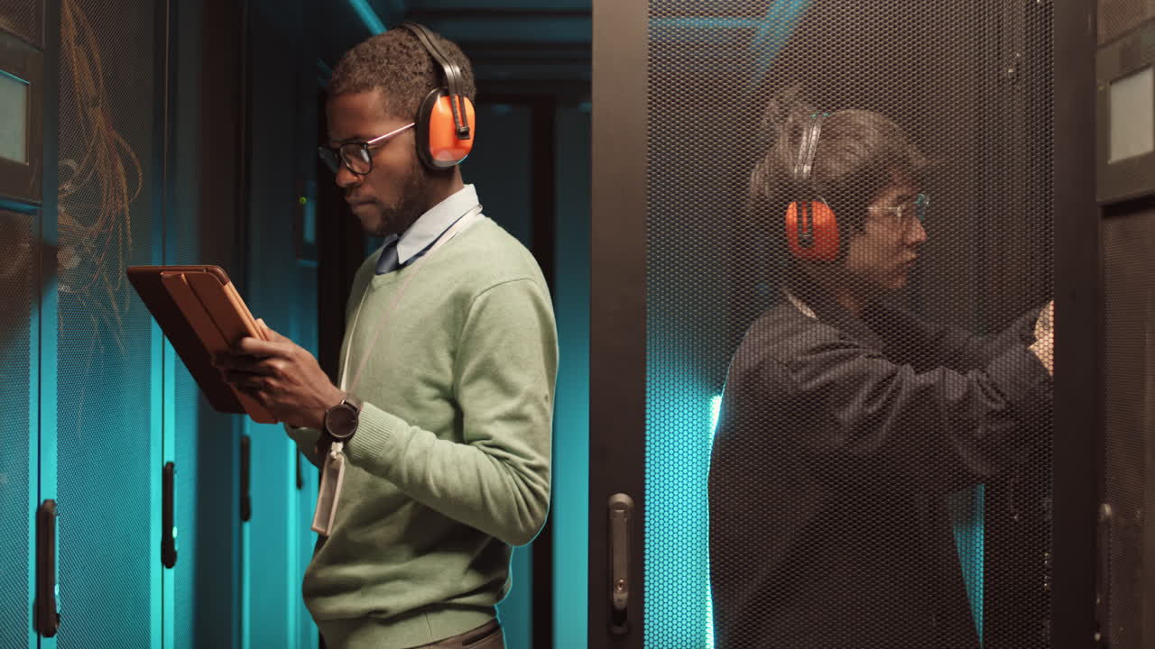 Pair of IT Engineers Working in Server Room