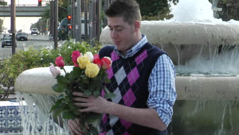 a man waits excitedly at a fountain with flowers and a heartshaped box 1