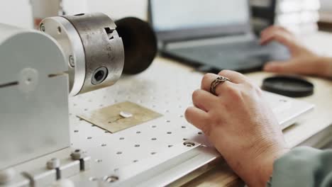 busy caucasian female worker using machine for scanning jewellery with laptop in slow motion