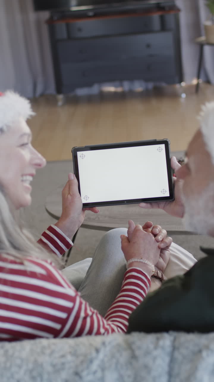 Vertical video of senior caucasian couple using tablet with copy space, slow motion