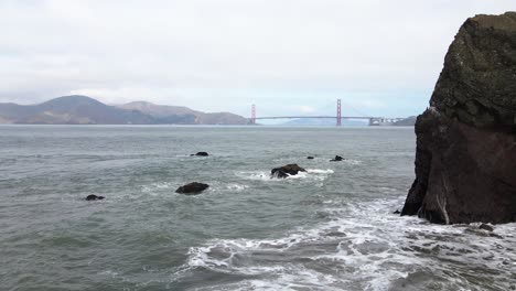 Aerial-view-low-over-the-coast-of-San-Francisco,-towards-the-Golden-gate-bridge---tilt,-drone-shot