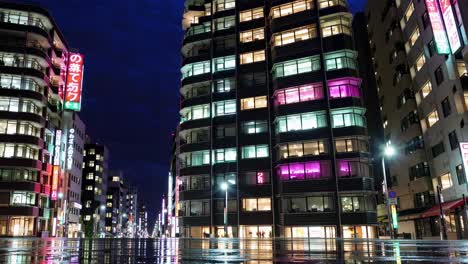 night cityscape of a japanese city with illuminated buildings and wet street reflections