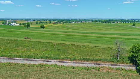 an aerial view of the farm countryside with a single rail road track on a curve on a beautiful sunny day