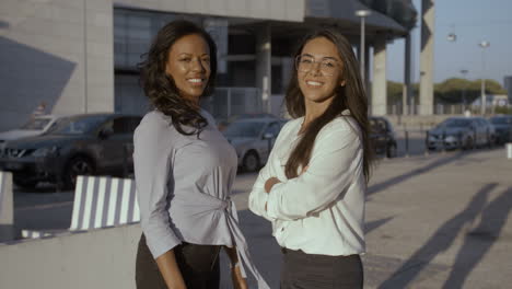 black woman smiling and posing with her colleague with crossed arms