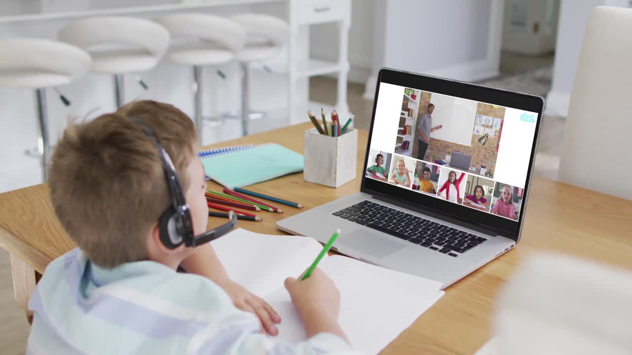 Schoolboy using laptop for online lesson at home, with diverse teacher and class on screen