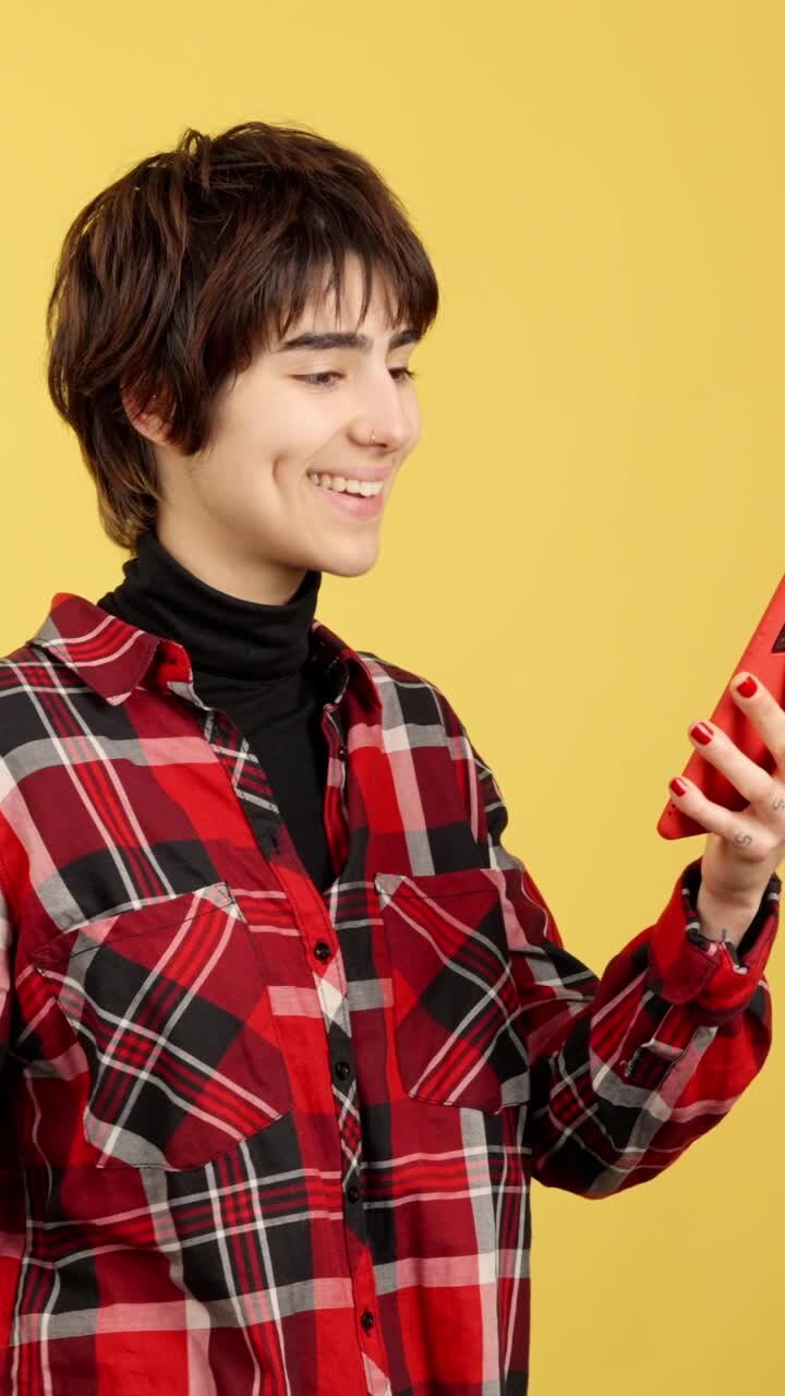 Young woman smiling while looking at her red smartphone