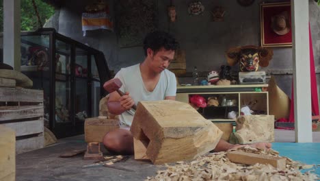 indonesian man sitting at home carving in solid wood