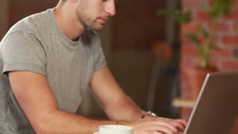 Ernster-Hipster-Mann,-Der-An-Einem-Laptop-Arbeitet