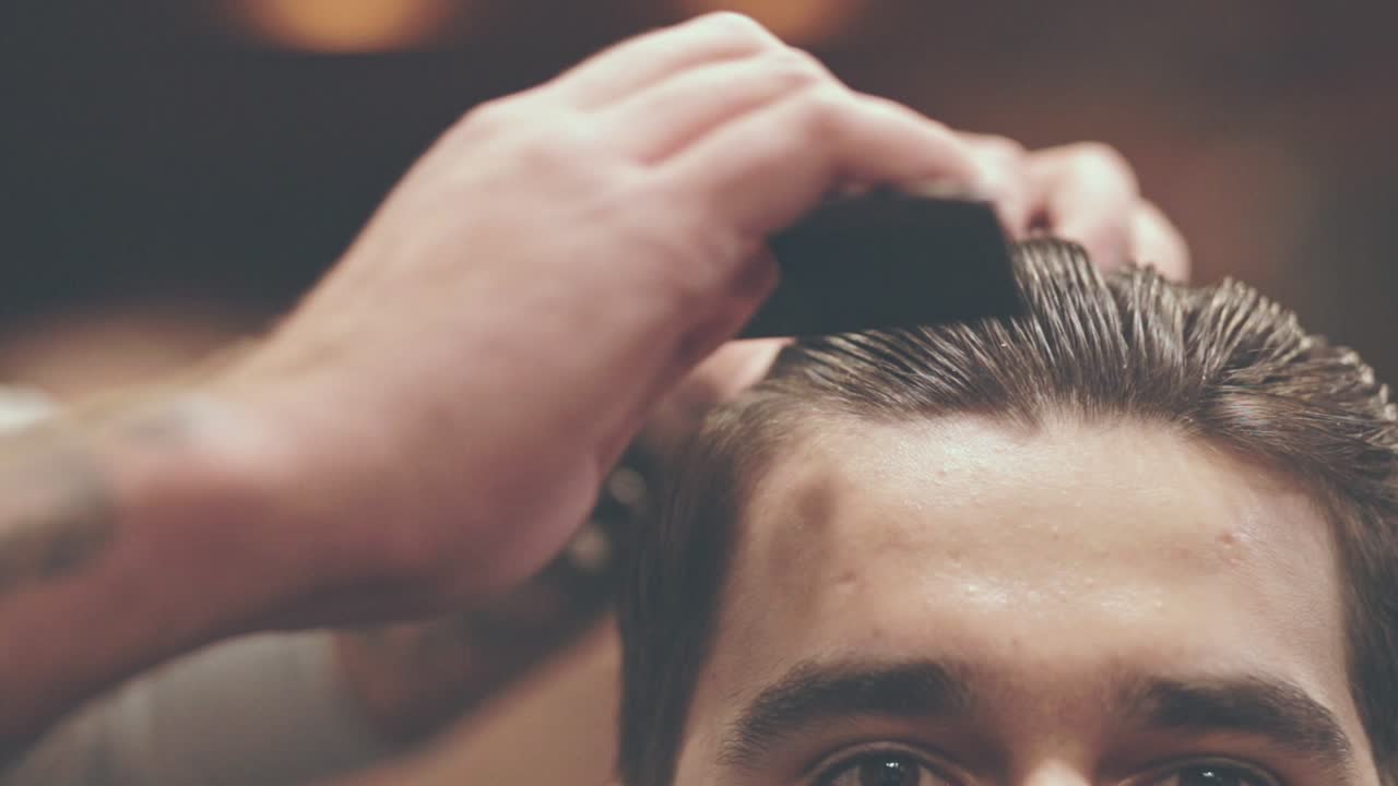 Uomo che si pettina i capelli. Taglio da barbiere. Acconciatura. Parrucchiere che acconcia i capelli.